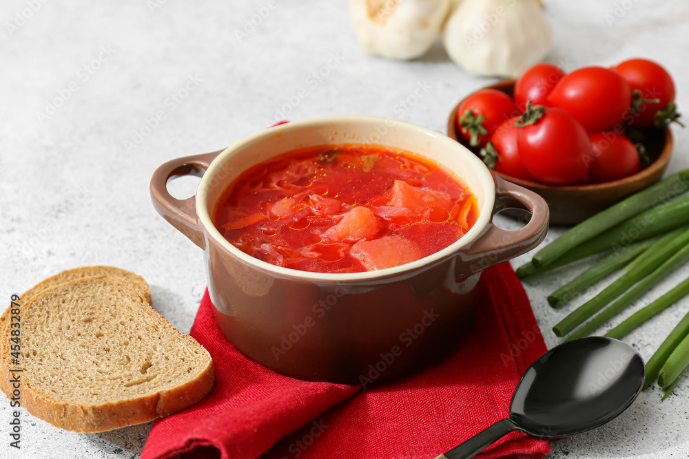 Pot of tasty borscht and ingredients on light background Pot of tasty borscht and ingredients on light background