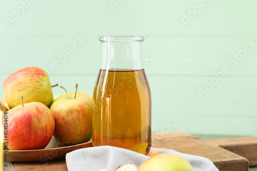 Bottle of tasty apple juice on color wooden background, closeup
