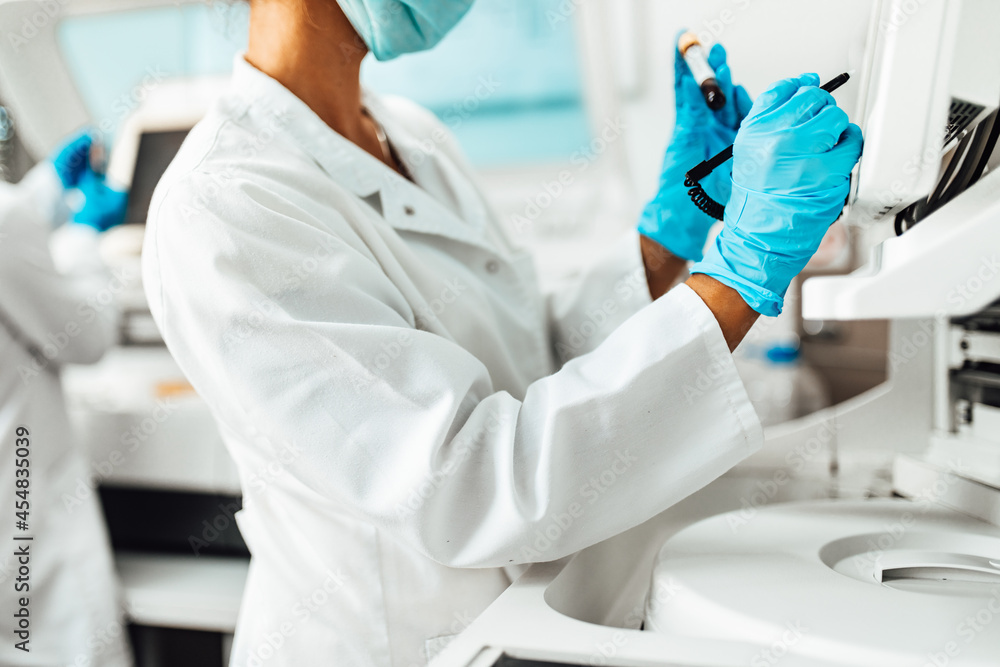 Female scientist or technician with a face protective mask working in modern laboratory. Female scientist or technician with a face protective mask working in modern laboratory.