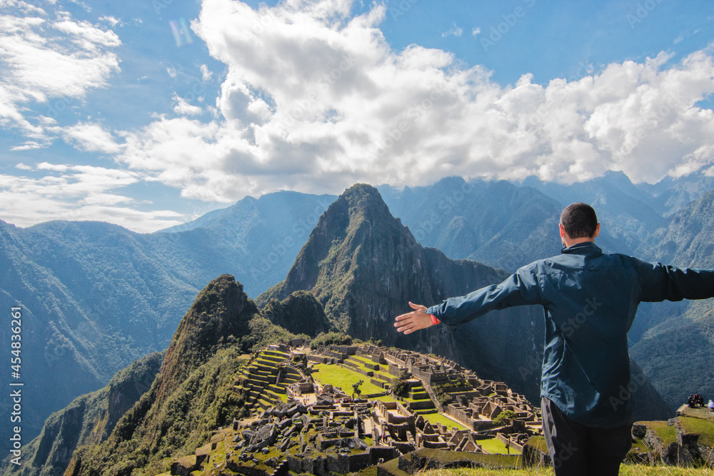 unknown latin man on the mountain with open arms staring at Machu Picchu, Peru