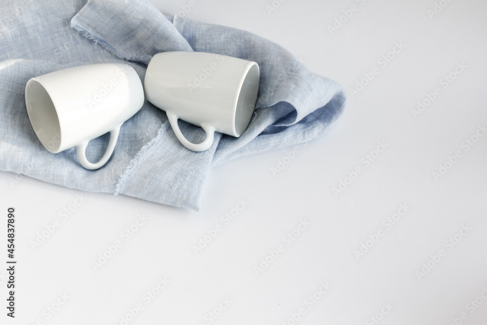 Obraz premium Dishes for a couple. Two porcelain cups for double espresso lie on a linen towel and dry after washing.