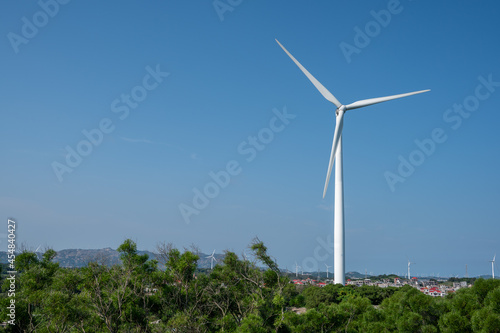 The wind turbine in operation on the mountain is under the blue sky