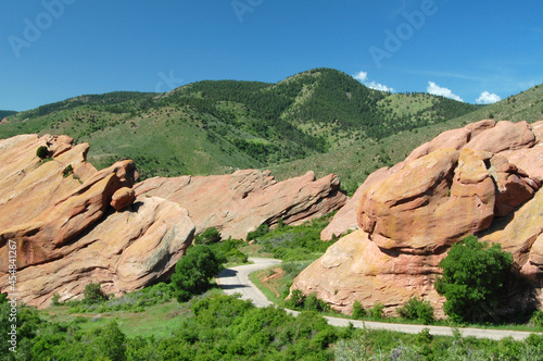 Colorado summer landscape at Red Rocks Park with road between sandstone geological formations and green hills and lush vegetation photo