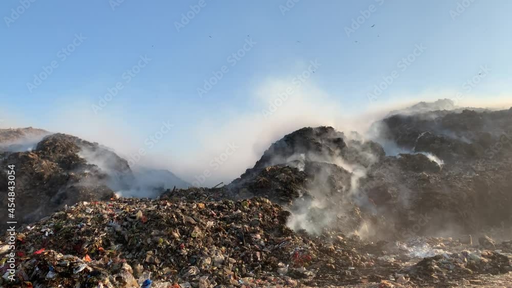 Burning pile of garbage at dump ground or landfill releasing toxic smoke in environment and polluting air Burning pile of garbage at dump ground or landfill releasing toxic smoke in environment and polluting air