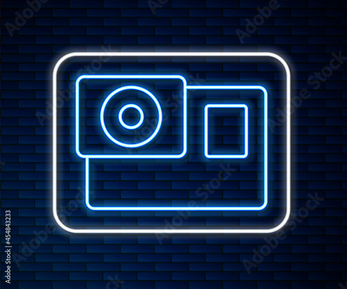 Glowing neon line Action extreme camera icon isolated on brick wall background. Video camera equipment for filming extreme sports. Vector