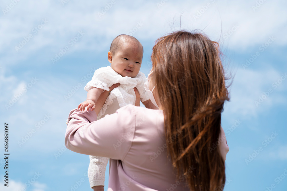 Fototapeta premium 赤ちゃんを高い高いする女性(マスク)