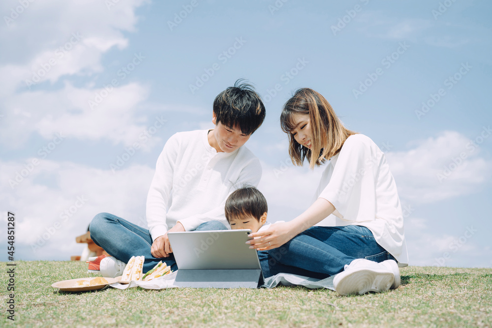 空とタブレットPCを使う家族
