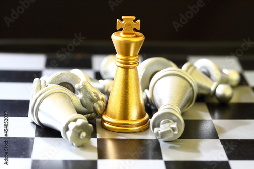 gold King chess surrounded by a number of fallen silver chess pieces , business strategy concept