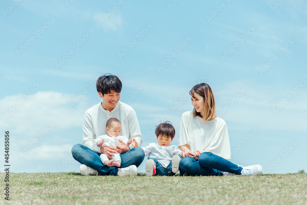 空と芝生に座る家族・ファミリー（4人）
