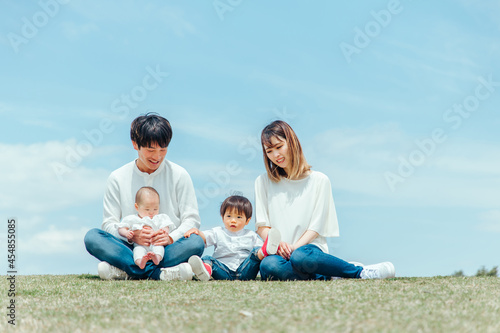 空と芝生に座る家族・ファミリー（4人）
