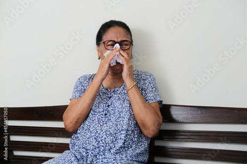 Elderly Asian woman sitting in a couch while crying sad photo