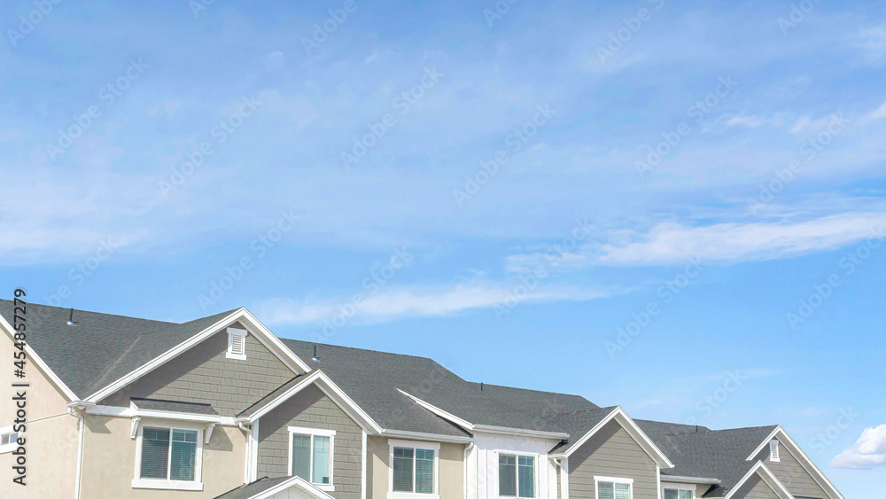 Pano Front view of townhouses against blue sky on a suburban neighborhood landscape Pano Front view of townhouses against blue sky on a suburban neighborhood landscape