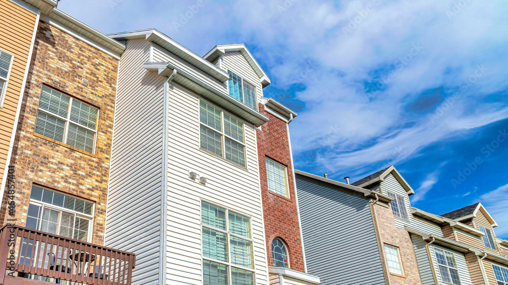 Fototapeta premium Pano Townhouses on a sunny day setting with balconies overlooking scenic skyscape