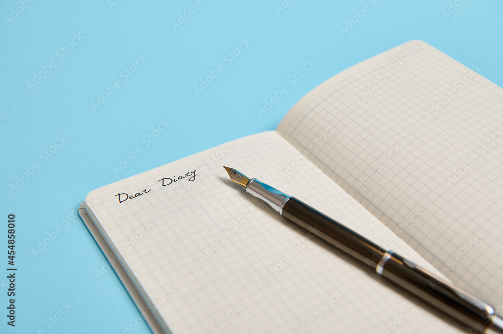 Cropped studio shot of an open notepad with word Dear Diary and an ink pen isolated on blue background with copy space Cropped studio shot of an open notepad with word Dear Diary and an ink pen isolated on blue background with copy space