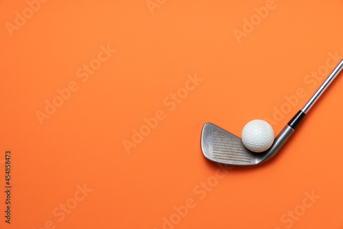 golf ball and golf club on orange background, sport concept