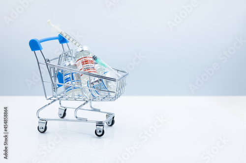 Covid vaccine dose bottle place in the shopping cart trolley for Coronavirus with health medicine industry business concept