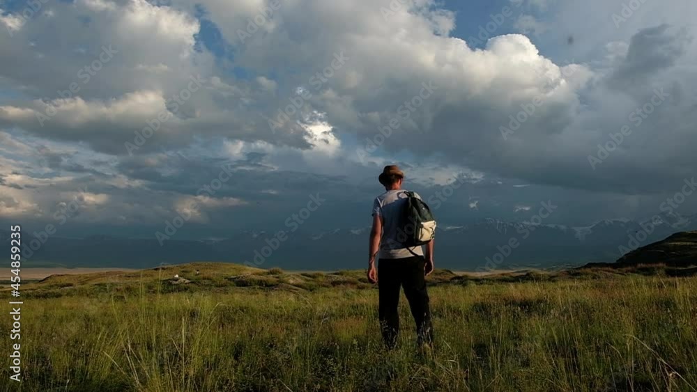 Adult male hipster tourist with backpack on his back in is walking. hiker looks with pleasure at mountain landscapes and rests enjoying fresh air and freedom. trip to the mountains. active recreation Adult male hipster tourist with backpack on his back in is walking. hiker looks with pleasure at mountain landscapes and rests enjoying fresh air and freedom. trip to the mountains. active recreation