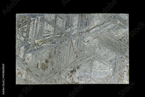 Acid-etched Muonionalusta meteorite plate with Widmanstetten patterns on a black background close up
