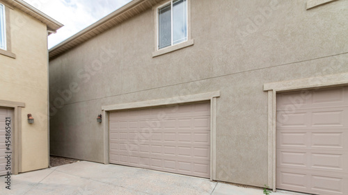 Pano Exterior of two buildings with concrete driveway, garage doors and windows
