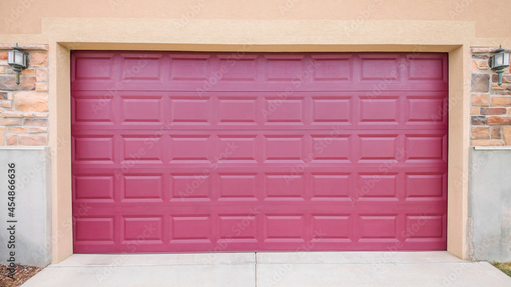 Pano Burgundy closed garage door with two wall lamps on a brick wall