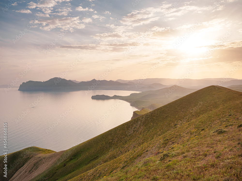 Stunning scenery in the sunset rays of the sea coast and mountains. Black Sea coast, view of Koktebel, massif Karadag Stunning scenery in the sunset rays of the sea coast and mountains. Black Sea coast, view of Koktebel, massif Karadag