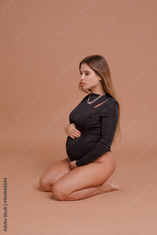 Beautiful pregnant young woman in studio on beige background Beautiful pregnant young woman in studio on beige background