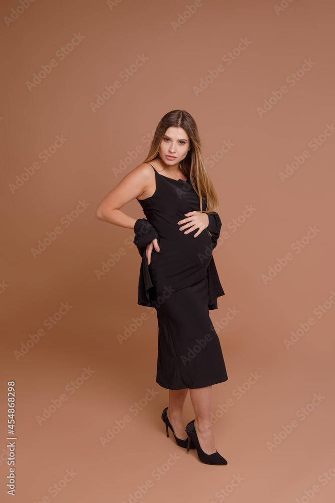 Beautiful pregnant young woman in studio on beige background Beautiful pregnant young woman in studio on beige background