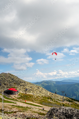 view of a mountain top shooted from Chopok, famous Low Tatra mountain with its beautiful scenery of summer surroundings with paraglider over Kamenna chalet photo