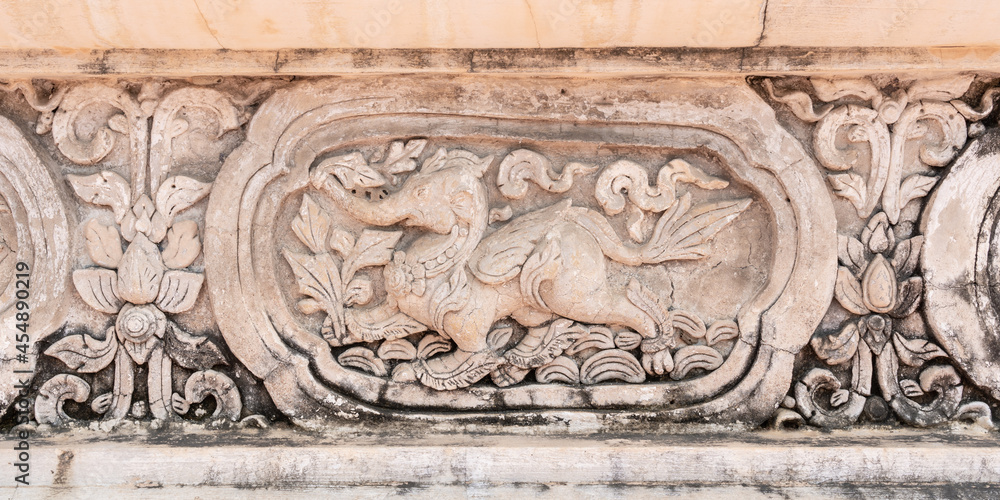 Beautiful ancient bas-relief stucco panel of a lion with elephant head, a mythological animal on wall of hor trai library in Wat Phra Singh buddhist temple, famous landmark of Chiang Mai, Thailand