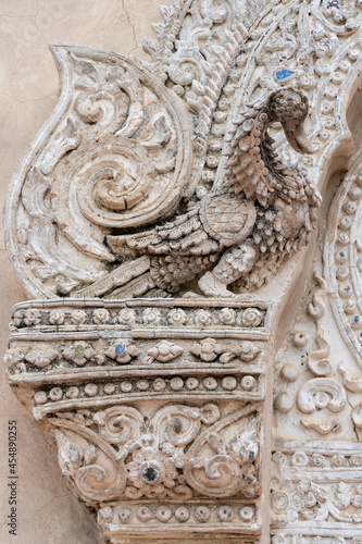 Beautiful ancient bas-relief stucco decor of a mythological swan bird around door of hor trai library in Wat Phra Singh buddhist temple, famous landmark of Chiang Mai, Thailand