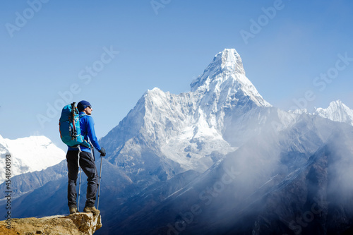 Vászonkép Young male hiker with backpack relaxing on top of a mountain during sunny summer