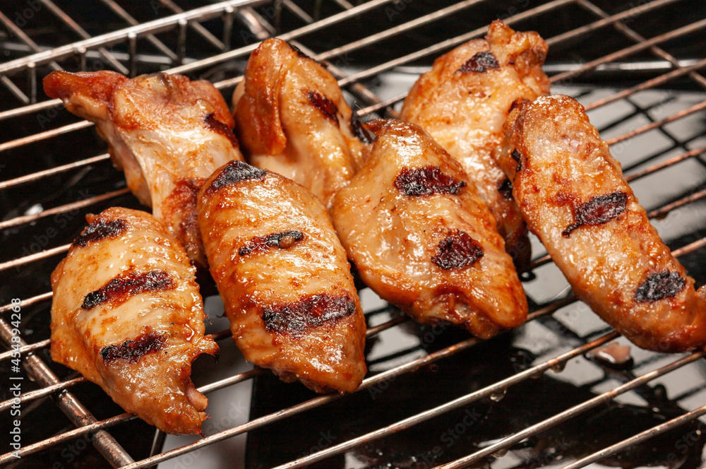 Delicious hot grilled chicken wings on grid grill.