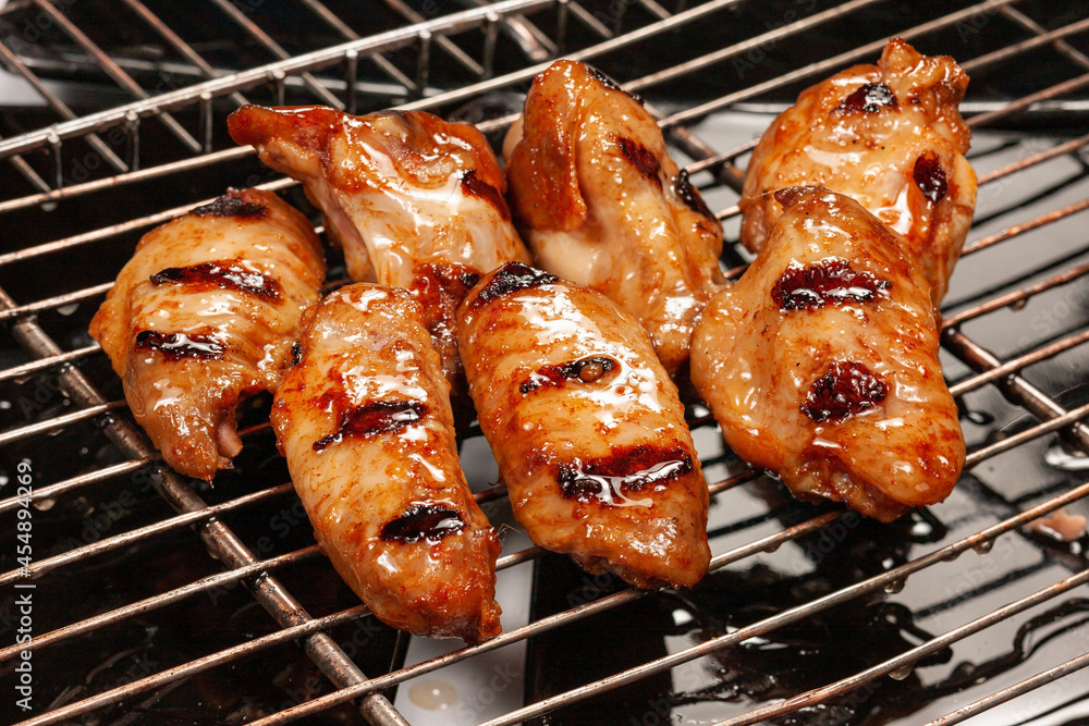 Delicious hot grilled chicken wings on grid grill.