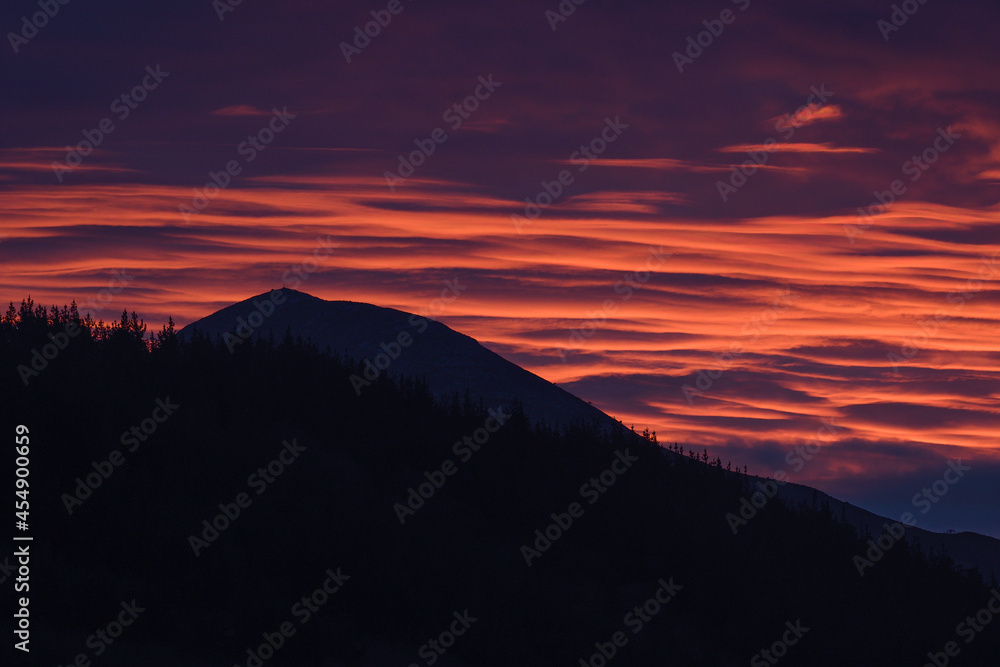Reddish sunrise with the silhouette of Pico de la Cruz in the background Reddish sunrise with the silhouette of Pico de la Cruz in the background
