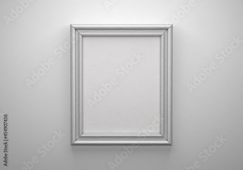 The white color picture vertical frame on white wall with textured blank canvas, 3D mockup
