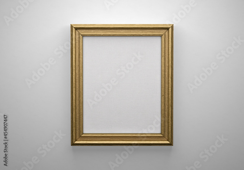 The bronze color picture vertical frame on white wall with textured blank canvas, 3D mockup