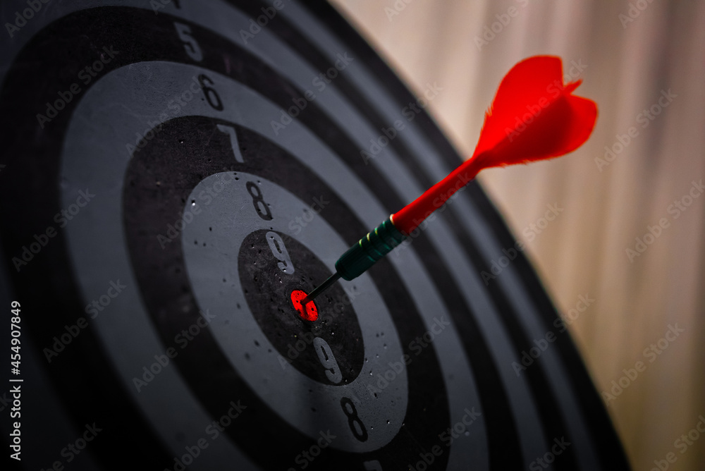 Close up shot of the dart arrow hit on bulleyes of dartboard to represent that the business reached the target of company with dark tone picture style. Target and goal as concept.
Close up shot of the dart arrow hit on bulleyes of dartboard to represent that the business reached the target of company with dark tone picture style. Target and goal as concept.