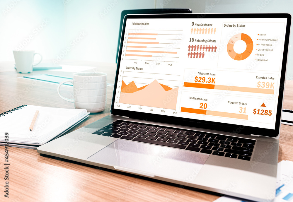 Mock up sales summary slide show presentation on display laptop with notebook and coffee cup on table in meeting room