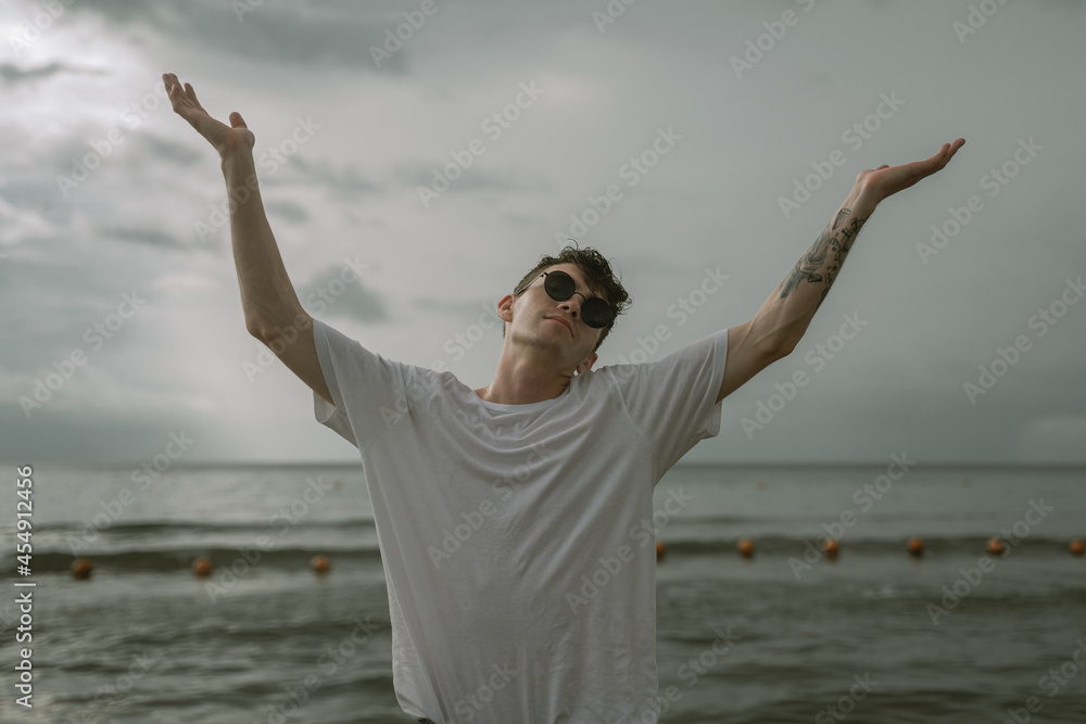 young guy raised his hands looking up, addresses to heaven young guy raised his hands looking up, addresses to heaven