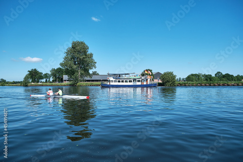Amersfoort, Hoogland, the Netherlands June 13, 2021, Bicycle boat, ferry eemland on the river Eem with canoeist and a dike and blue sky in the background. Boat trip through the Eemvallei and 't Gooi
