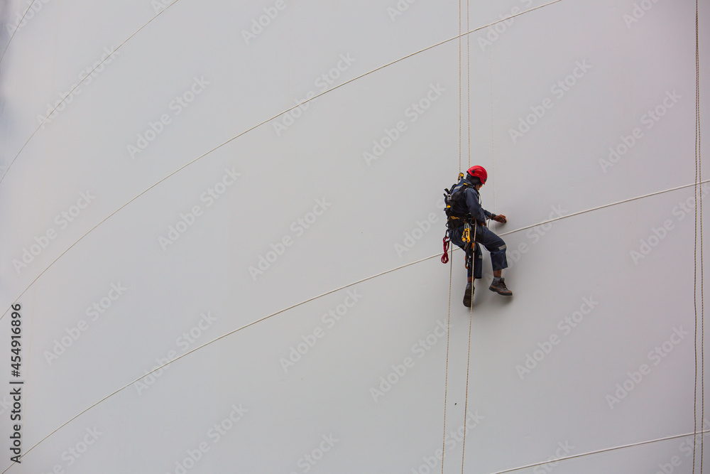 Male workers control rope down height tank rope access inspection of thickness shell plate storage tank.