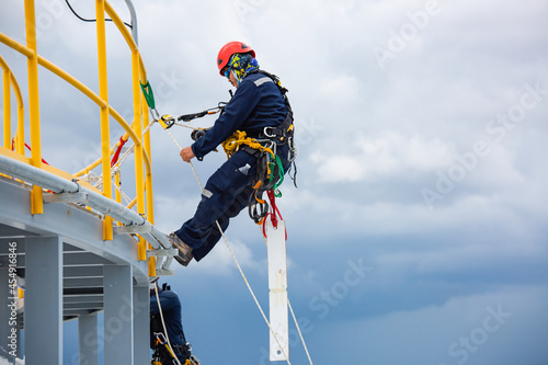 Male workers control rope down top roof tank rope access inspection of thickness shell plate storage tank gas