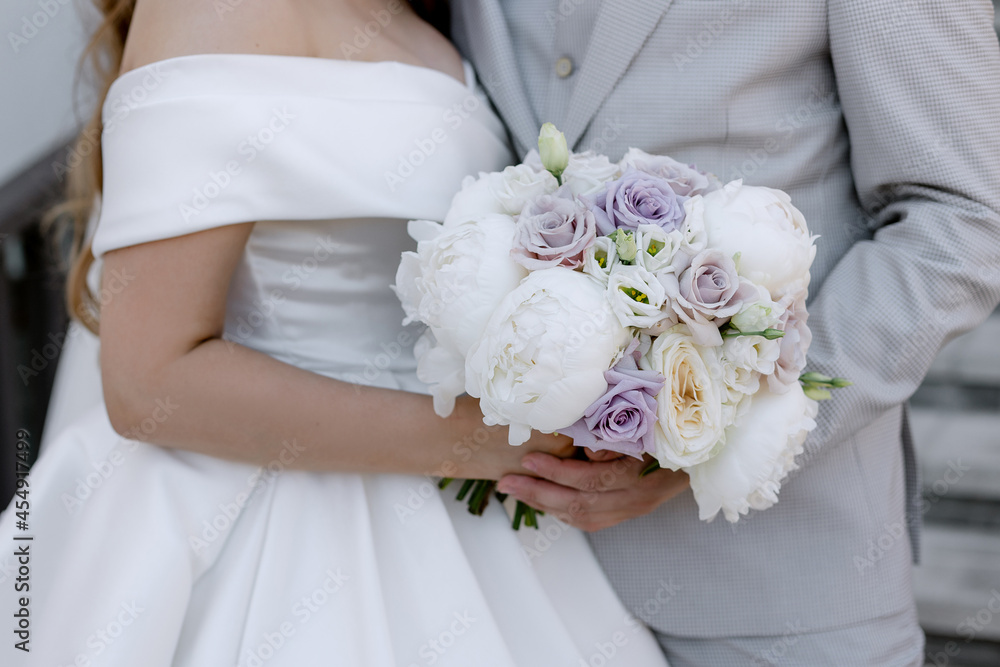 Wedding bouquet of beautiful flowers In young female hands of the bride Elegant white dress for the wedding ceremony Newlyweds holiday Wedding bouquet of beautiful flowers In young female hands of the bride Elegant white dress for the wedding ceremony Newlyweds holiday