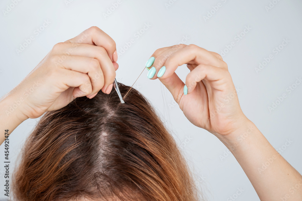 Fototapeta premium Caucasian woman finds gray hair and removes it with tweezers. Signs of aging.