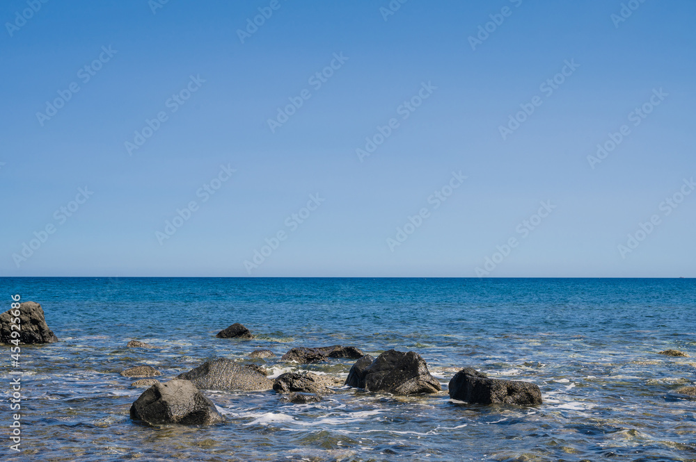 Scenic landscape of Huge black stones in Aegean sea. Blue sky. Unique beautiful nature in Greece.