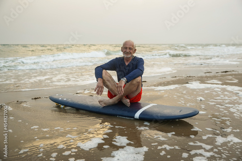Photography Handsome adult man walks with a surfboard on the seashore
