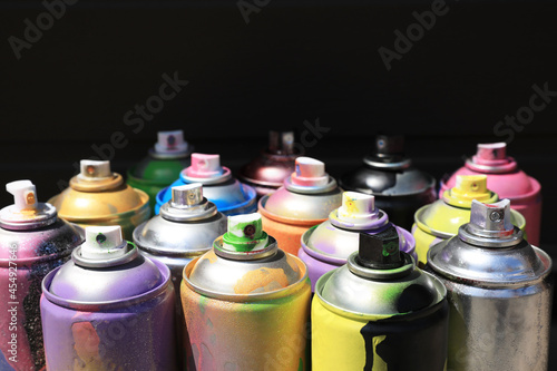 Used cans of spray paint on dark background. Graffiti supplies