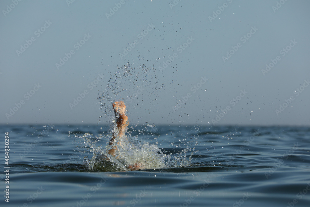 Drowning woman's leg sticking out of sea