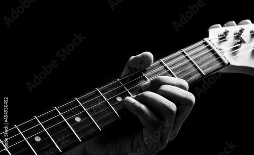 Fotografiet close up male musician left hand playing chord on electric guitar neck