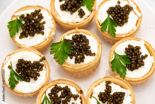 Black caviar in tartlets on a light background. Healthy food concept. Copy space.